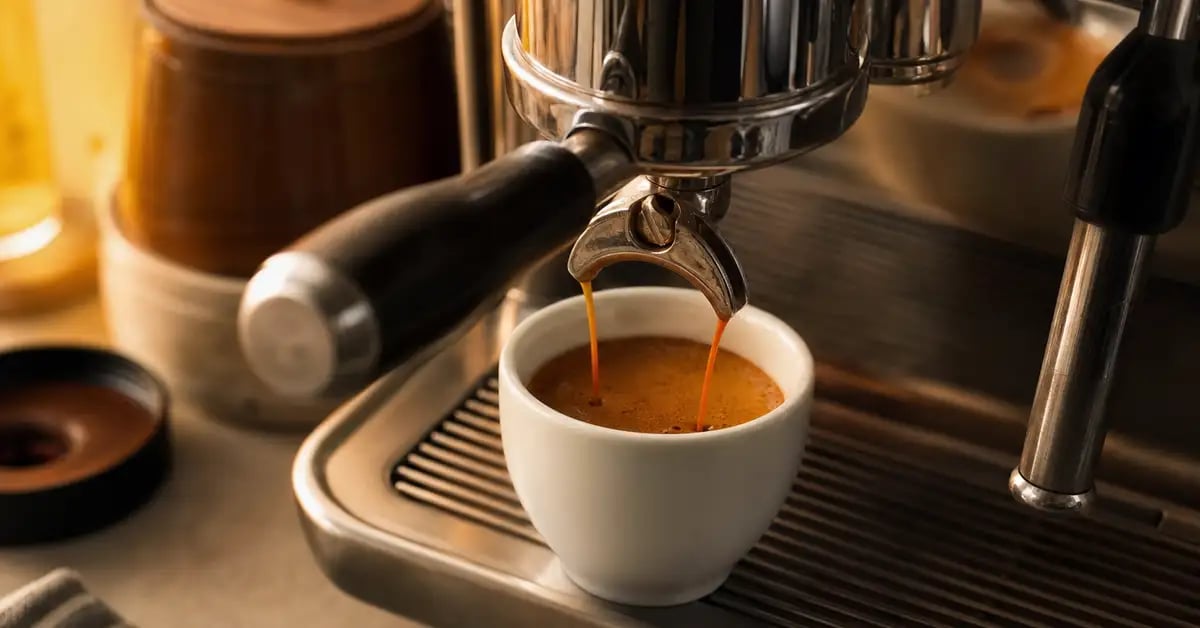 Espresso shot being pulled into a white ceramic cup with rich dark crema forming